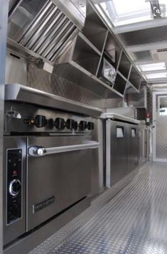 an industrial style kitchen with stainless steel appliances and floor tiles on the walls, along with skylights