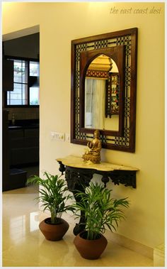 two potted plants sitting on top of a table in front of a large mirror