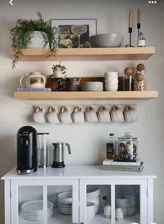 some shelves that have plates and cups on top of each other in front of a wall