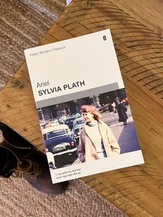 a book sitting on top of a wooden table next to sunglasses and a pair of black eyeglasses