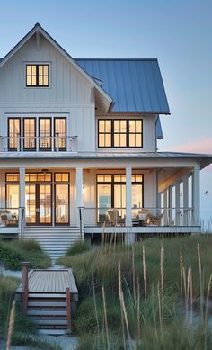 a large white house sitting on top of a lush green field next to the ocean