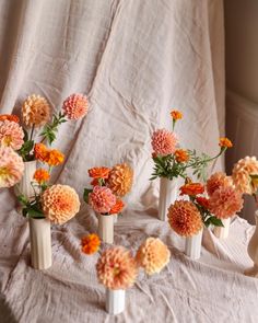 small vases with flowers in them on a tableclothed cloth covered bed sheet