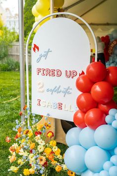 a sign that is on the grass near some balloons