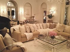 a living room filled with furniture and a chandelier hanging from the ceiling above