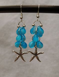 Let the spirit of the tropics surround you as you wear these earrings! The blue tear drop glass beads represent the ocean water. The pewter star fish adds the finishing touch French ear wire is silver plated. Beach Dangle Teardrop Earrings With Ear Wire, Silver Drop Earrings With Starfish Charm, Silver Ocean-inspired Earrings With Starfish Charm, Ocean-inspired Silver Earrings With Starfish Charm, Nickel-free Starfish Earrings Ocean-inspired, Beach Teardrop Jewelry With Dangling Beads, Beach Jewelry With Teardrop Dangling Beads, Ocean-inspired Starfish Dangle Jewelry, Teardrop Dangling Beads Jewelry For Beach