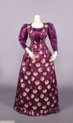 2-pc magenta patterned silk in chrysanthemum motif w/ faux vest bodice front over silk satin long sleeve, knife pleated CF panel & removable inset pleated & ruched yoke, pleated skirt w/ box pleated self-ruffle to hem, bodice B 32”, L 16”, skirt W 23”, L 44”, (6” seam opening CF bodice, loose stitching b/t CF bodice panels, 2” & 2.5” seam openings CB bodice, few scattered sm wear spots & tiny holes, 1” stain CB Wband) t/w 7 remnants. Deaccessioned by the Valentine Museum. Silk Dinner Gown, 1890 Dresses, Vest Bodice, 1890 Dress, Faux Vest, Dinner Gown, Satin Long Sleeve