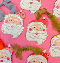 paper santas with bows and ribbons on a pink background