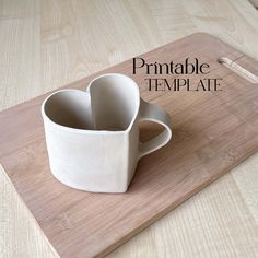 a heart shaped mug sitting on top of a cutting board