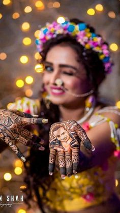 a woman with henna on her hands and lights in the back ground behind her