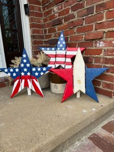 three wooden stars painted red, white and blue sitting on the front step of a house