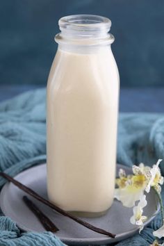 a bottle of milk sitting on top of a plate next to two sticks and a flower