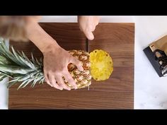 pineapple being cut into pieces on a cutting board with a knife and other food items