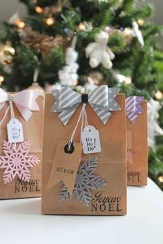 three brown bags with snowflakes on them are sitting in front of a christmas tree