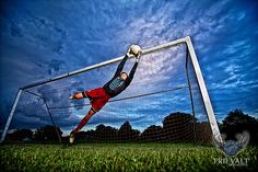 a soccer goalie diving for the ball in front of his goal net at night