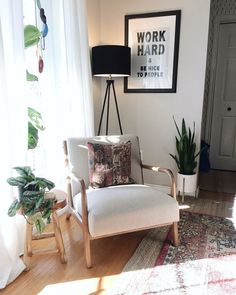 a white chair sitting on top of a hard wood floor next to a potted plant