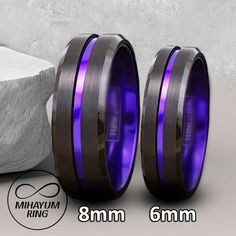 two men's wedding bands with purple and black ceramic inlays are shown