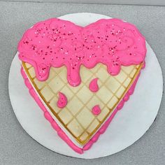 a heart shaped cake with pink icing on a white plate