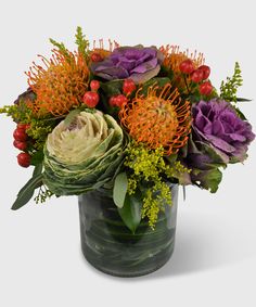 an arrangement of flowers in a vase on a white background, including orange and purple flowers