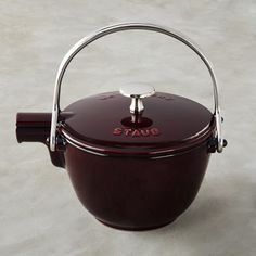 a red pot with a metal handle sitting on top of a table