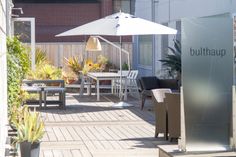 an outdoor patio with tables, chairs and umbrellas on the decking area in front of a building