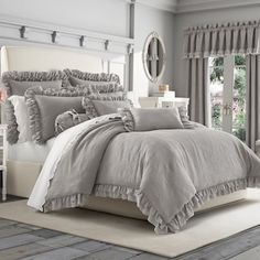 a bed with grey ruffled comforter and pillows