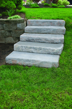 stone steps lead up to the grass in front of a house