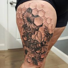 a woman's thigh with flowers and honeycombs on her thighs, in black and grey