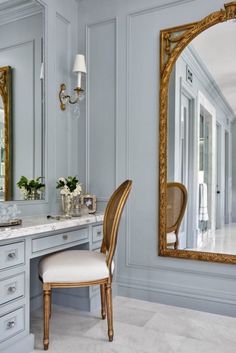 a chair sitting in front of a vanity with a large mirror on it's wall