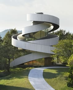 a white spiral shaped building with trees in the background