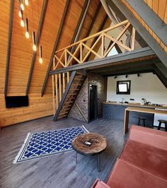 an open loft with wooden walls and stairs leading up to the second floor, along with red couches