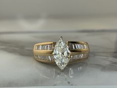 an engagement ring with a pear shaped diamond and baguettes set in yellow gold