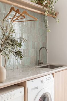 a washer and dryer in a kitchen with green tile backsplashing