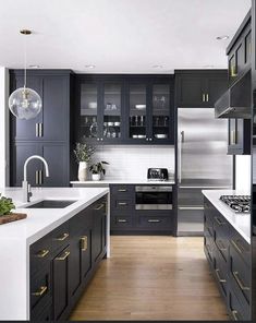 a large kitchen with black cabinets and white counter tops, gold pulls on the handles