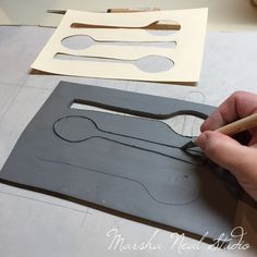 a person is cutting out some paper shapes with a pencil and scissors on the table