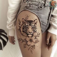 a woman's thigh with a tiger and flowers tattoo on the side of her leg