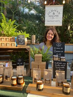 a woman standing in front of jars of honey on display at an outdoor market stall