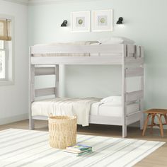 a white bunk bed sitting in a bedroom next to a wooden table and chair on top of a rug