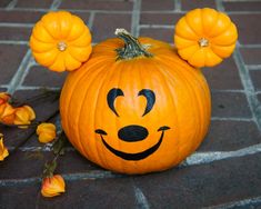 a mickey mouse pumpkin sitting on top of a brick floor