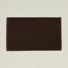 a brown and black checkered rug on a white wall