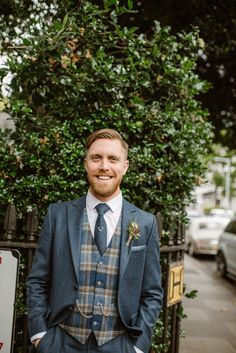 a man in a suit and tie standing next to a fence