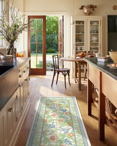 a kitchen with an area rug on the floor and wooden cabinets in front of it