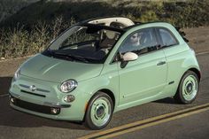 a small green car driving down the road