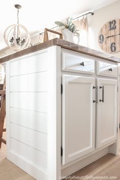 a kitchen island with white cabinets and a clock on the wall