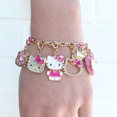 a hello kitty bracelet on someone's hand with pink and white charms attached to it