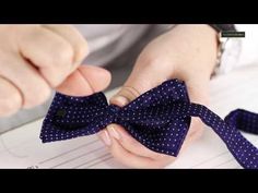 a person tying a bow tie on top of a piece of paper