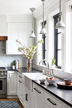 a kitchen with white cabinets and black counter tops, an oven, dishwasher, sink, and window