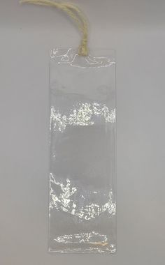 an empty clear plastic bag hanging from a string on a white wall with a tag attached to it