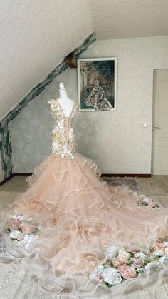 a dress on display in an attic with flowers all over the floor and behind it is a mannequin