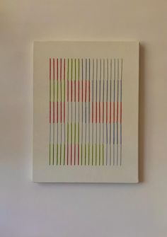 a white square with red, green and blue lines on it is hanging on the wall