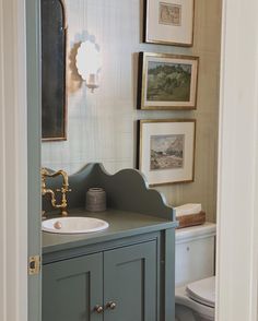 a bathroom with a sink, toilet and pictures on the wall above it's door